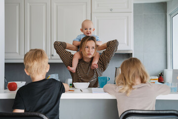 Young exhausted woman with three children at home.