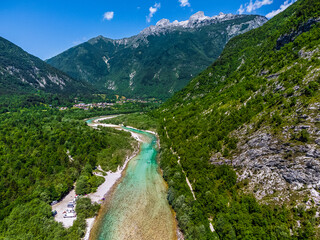 Soca Valley, Slovenia - Aerial view of the emerald alpine river Soca on a bright sunny summer day with Julian Alps, blue sky and green foliage