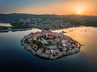 Primosten, Croatia - Aerial view of Primosten peninsula and old town on a sunny summer morning in Dalmatia, Croatia. Blue and golden sky at sunrise on the Adriatic sea coast