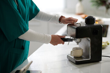 Hands of woman using coffee machine when making cup of beverage in the morning