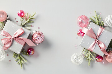 Obraz na płótnie Canvas Christmas gift boxes adorned with elegant pink ribbon bows, shiny baubles, and fir branches. Modern and stylish holiday design in pink and silver tones. Ideal for luxury celebrations