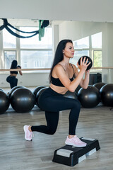 Fototapeta na wymiar Fit caucasian young woman in sportswear doing step aerobics exercise at fitness studio