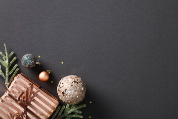Christmas composition on black background featuring festive elements like stylish gift box, copper...