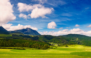 the nature mountain ridge landscape view is a green grass meadow field and highland hill mountain countryside with white cloud cloudscape on a blue beautiful bright sunlight sunny sky background