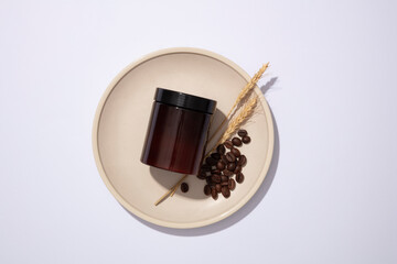 Top view of an amber plastic jar with coffee beans and ear of wheat placed on round ceramic dish on...