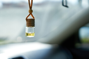 Air freshener hanging from a car mirror, on a blurred background. Aromatic oil.