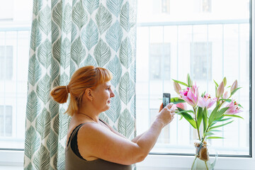 woman photographing bouquet flowers with smartphone