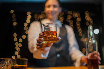 Bartender is pouring whiskey  glasses for customers beautiful night.