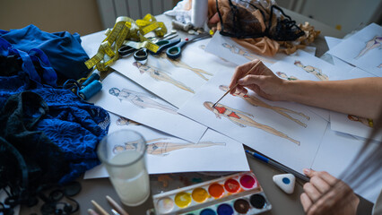 Woman drawing sketches of swimwear and underwear in watercolor. 