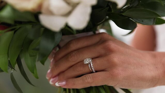Close up of brides diamond wedding ring while hold a flower bouquet in hand