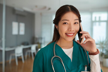 Portrait of cheerful medical nurse answering phone call from patient