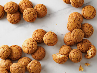 pile of cookie amaretti on white marble background - traditional Italian Sardinian pastry. Delicious amaretti biscuit cookies made from almond or apricot kernels with copy space
