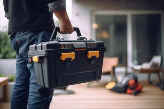 Close-up on an electrician carrying a toolbox while working at a house - domestic life concept