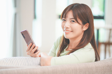 リビングでスマートフォンを操作する女性