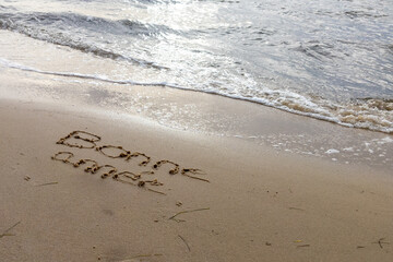 happy new year in french text sign means bonne annee written on a sandy beach wave and surf Vacation esort and recreation in nature Sea coast