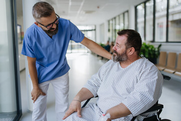 Close up of supportive doctor talking with worried overweight patient in wheelchair. Illnesses and diseases in middle-aged men's health. Compassionate physician supporting stressed patient. Concept of - obrazy, fototapety, plakaty