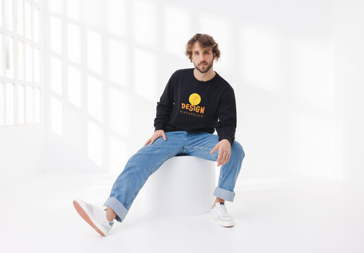 Mockup of man wearing customizable sweatshirt sitting on plinth