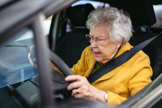 Focused senior woman driving car alone, holding steering wheel firmly. Safe driving for elderly adults, older driver safety.
