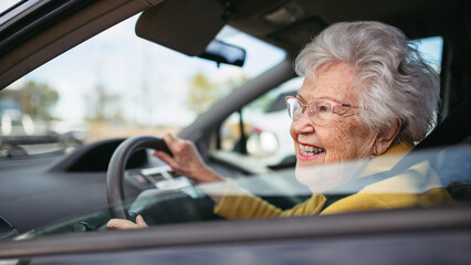 Happy senior woman driving car alone, enjoying car ride. Safe driving for elderly adults, older driver safety.