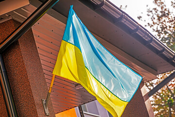 Ukrainian flag displayed on an architectural building, the context of war in Ukraine, and the theme...