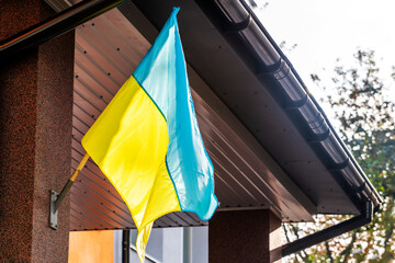 Ukrainian flag displayed on an architectural building, the context of war in Ukraine, and the theme of support for the nation during challenging times.