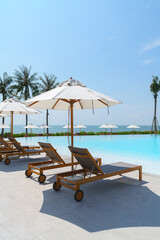Beautiful empty deck chair umbrella around outdoor swimming pool in hotel resort for travel vacation