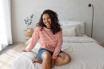 Portrait of adorable lovely african american young barefoot female with beautiful curly hair having...