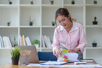 Fototapeta premium Asian woman holding a file and checks documents in the office.