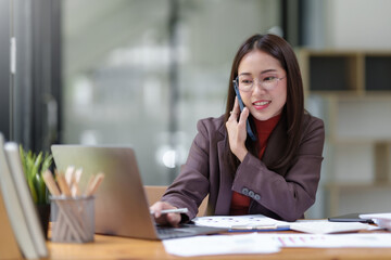 Asian businesswoman talking on the phone professionally in her office.