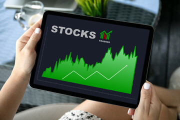 female hands hold computer tablet with stocks trading app screen