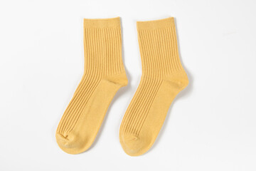 a pair of yellow socks laid out on white background