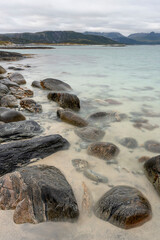 A serene summer evening by the turquise sea and rocky shore in Sommarøya island, in the Tromsø Municipality in Troms og Finnmark county, Norway.
