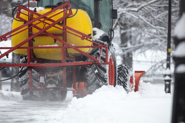 Tractor cleaning urban park paths on a cold snowy day.