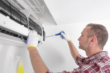 Service guy cleaning and maintaining air condition unit.