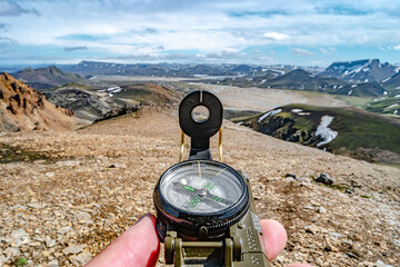 Beautiful colorful volcanic mountains Landmannalaugar and a compass to navigate in man hands, Iceland - obrazy, fototapety, plakaty