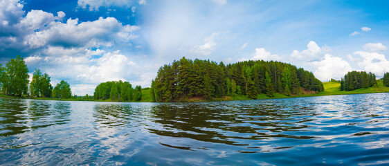 Tranquil lake landscape with scenic forest and blue sky.