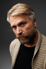 Obraz premium Blonde man with beard wearing knitted cardigan and looking at camera isolated on grey 