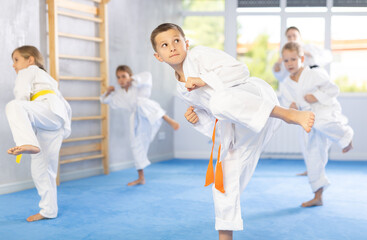 In gym, certified master coach conducts karate kata lesson with children boys girls team students group and shows sequence of actions when conducting close fight