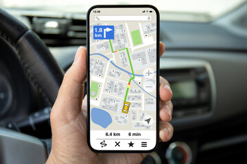 male hands hold phone with navigation application background wheel car
