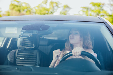 a woman behind the wheel of a car holds a fist