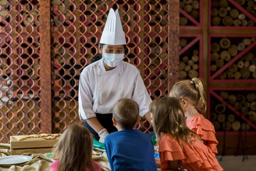 Children decorating Christmas biscuits and gingerbread cookies in kitchen together with chef. Kids cooking class. Merry Christmas and happy holidays