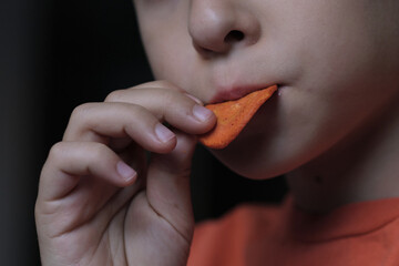 Close-up of a child's hand holding a spicy chip, capturing a quiet moment of simple indulgence and the small joys of childhood snacks.