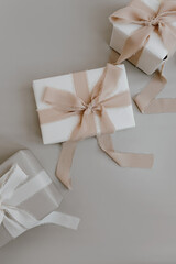 Holiday gift boxes packaging. Beautiful beige colour gifts with ribbon bows on white background. Flat lay, top view