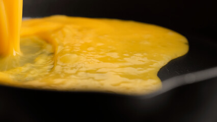 Pour mixed eggs in pan for cooking omelette, close up