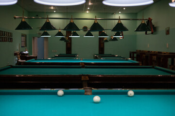 Empty billiard room with green tables illuminated by lamps. Beautiful game room for billiards...