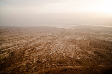 Aerial view of the lifeless Dead Sea coastline against foggy grey sky at dawn. Salty sea shore,...