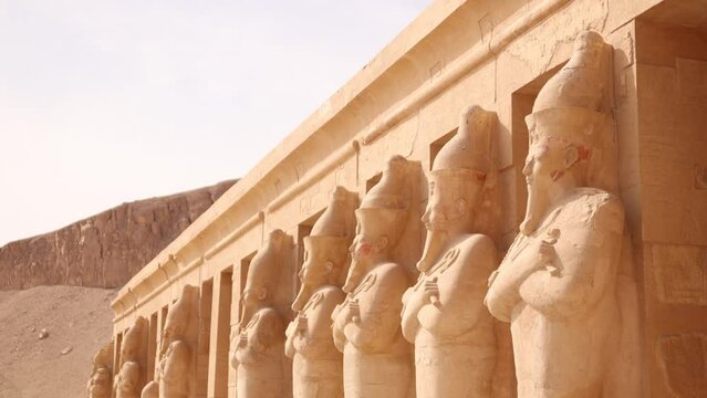 row of pharoah statues look out over the valley in front of Hatshepsut Temple in Luxor Egypt