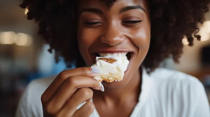 Gordijnen Young beautiful african woman eating a cake with cream closeup © Svetlana