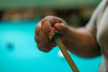 Close-up. A man's hand rubs the tip of a billiard cue with chalk for a more accurate shot. A man...