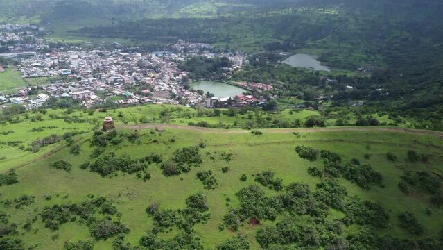 Aerial view of the Lord Shiva temple at the edge of the mountain top with the view of Trimbkeshwar town and Ahilya Dam in the background surrounded by lush greenery, Nashik, Maharashtra, India